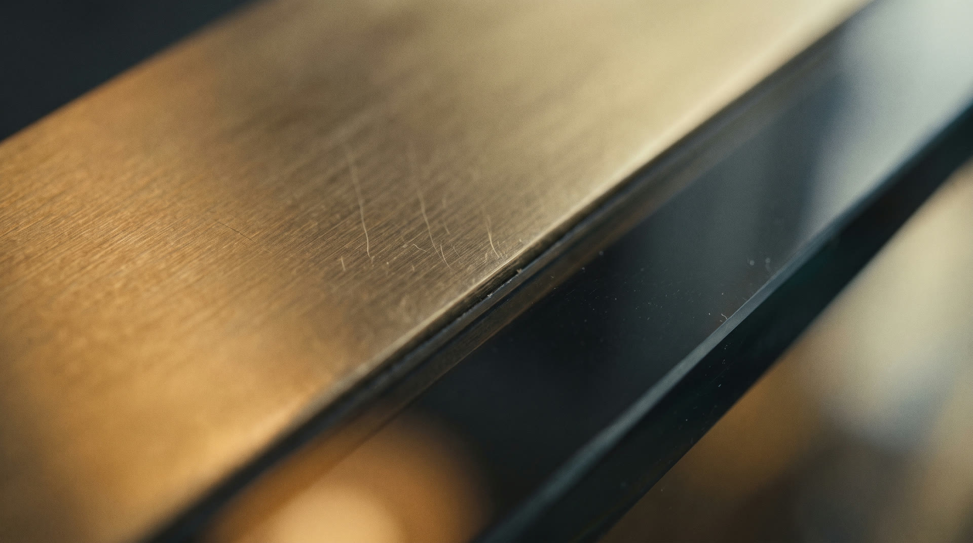 Macro of brushed brass detailing meeting a smoked glass edge